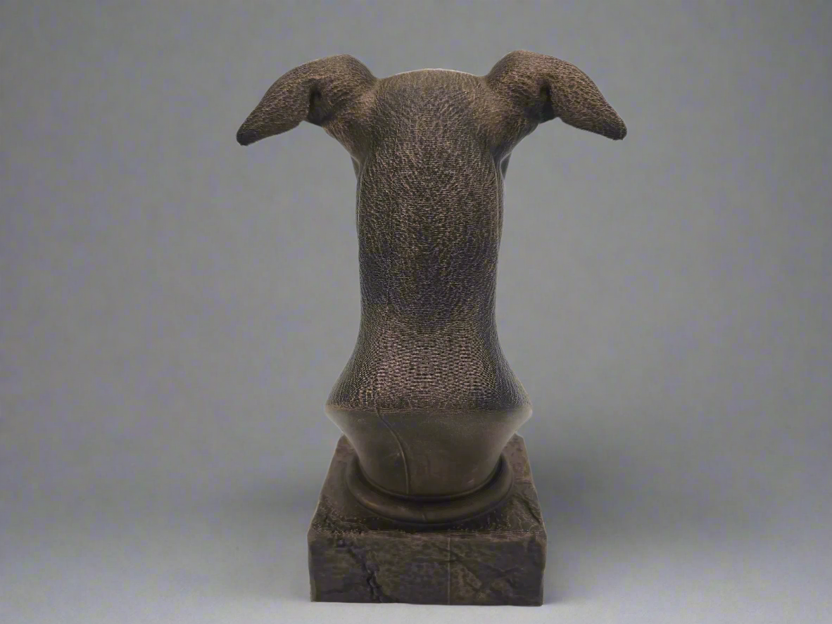 Bronze sculpture of a dog's head on a grey background