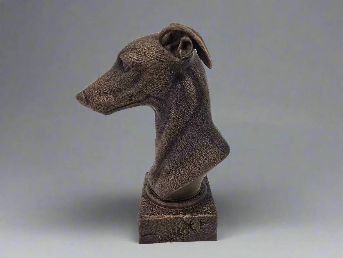 Bronze sculpture of a dog's head on a grey background