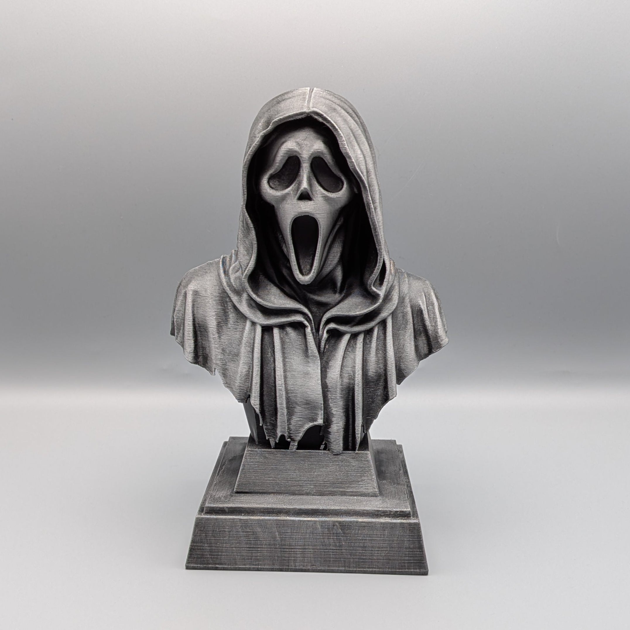 Front view of a 20 cm hand-painted silver Ghostface tribute bust with an elongated mask and hood on a pedestal base
