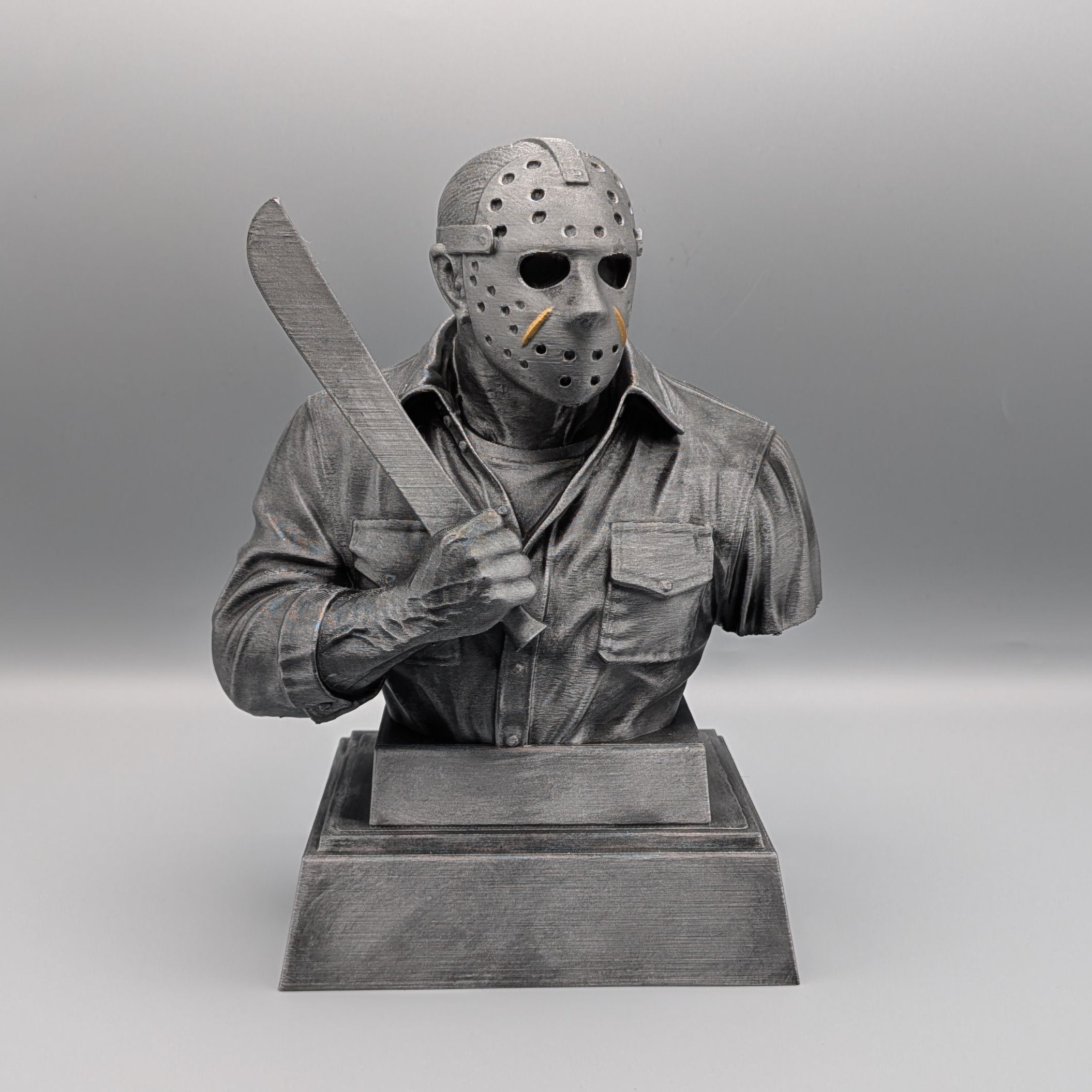 Front view of a 20 cm silver Jason Voorhees tribute bust holding a machete, with gold accents on the hockey mask