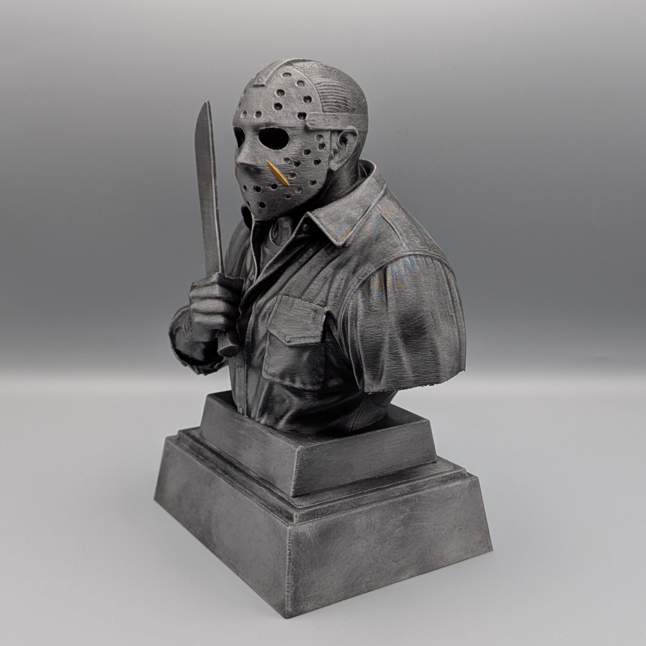 Left-hand side view of the silver Jason Voorhees tribute bust with hockey mask, gold accents and raised machete