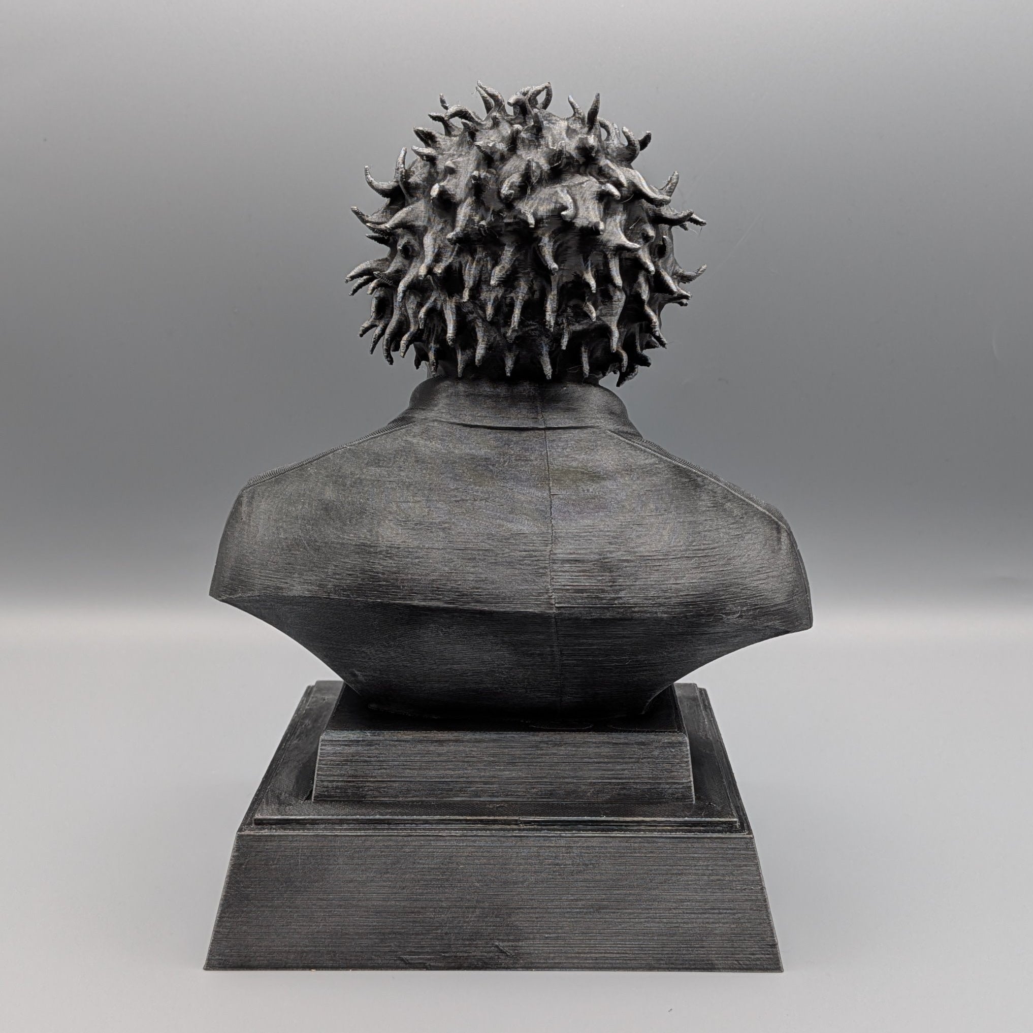 Back view of the silver Leatherface tribute bust showing the textured hair, shirt and solid pedestal base