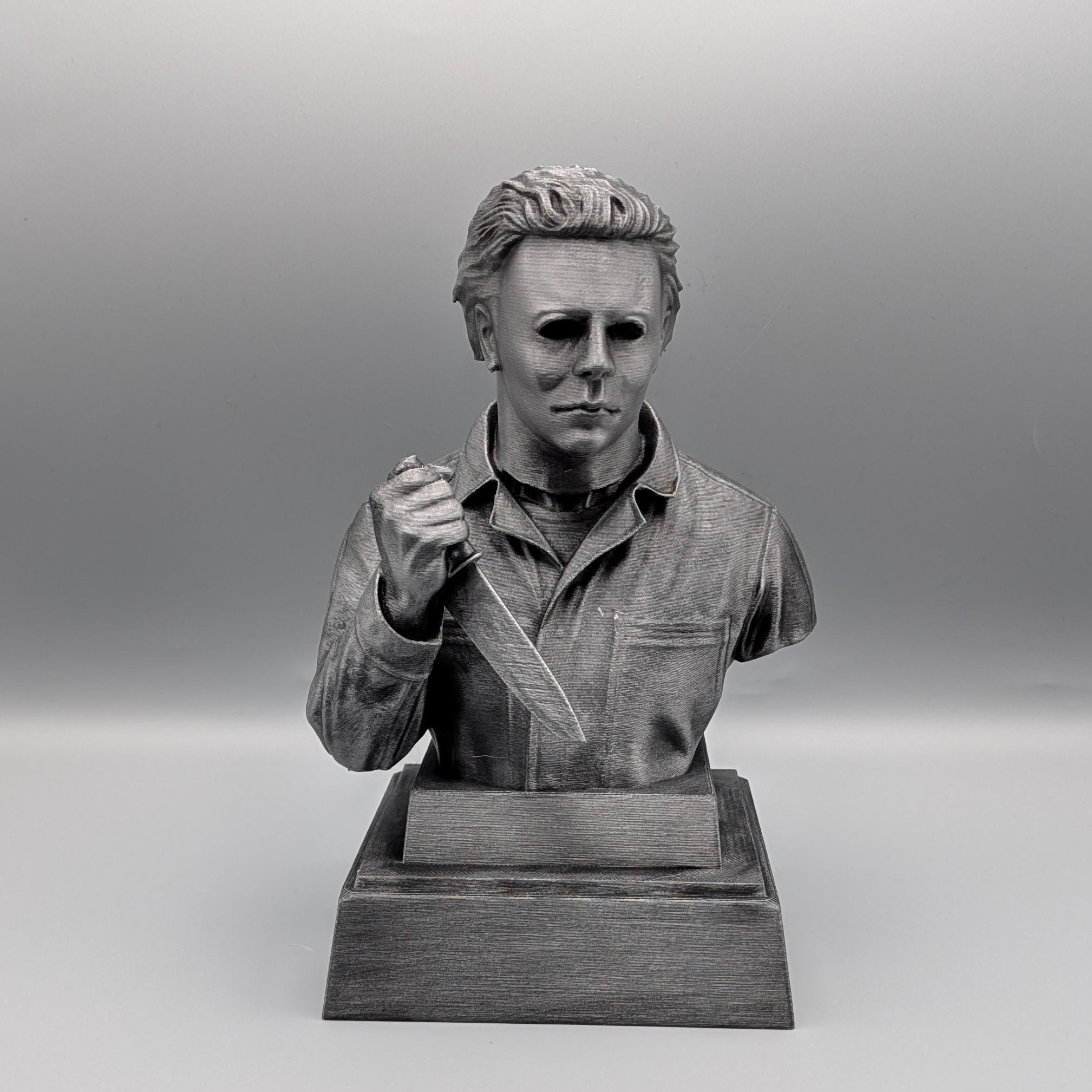 Front view of a 20 cm hand-painted silver Michael Myers tribute bust holding a knife on a pedestal base