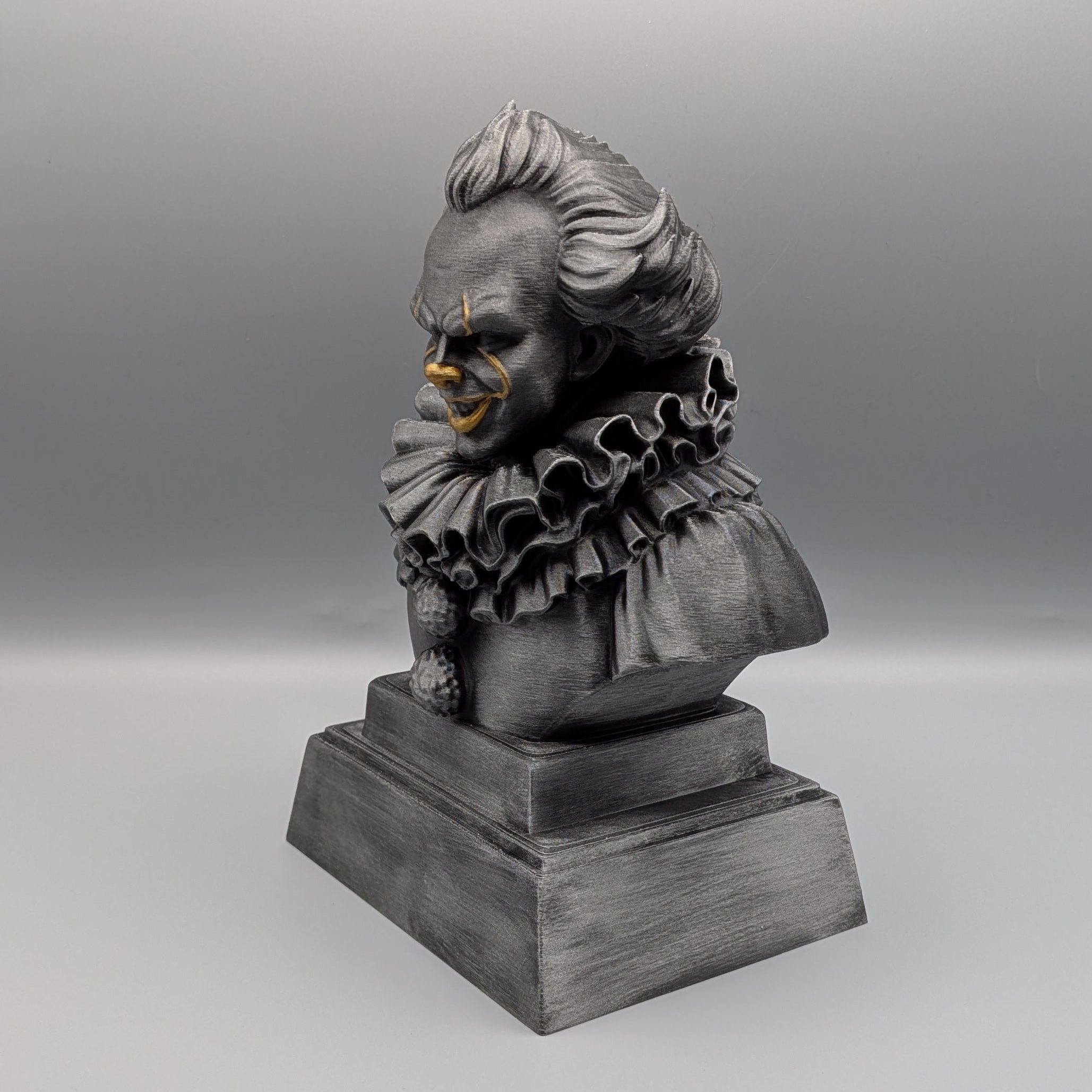 Left-hand side view of the hand-painted Pennywise tribute bust with layered collar, silver finish and gold facial accents