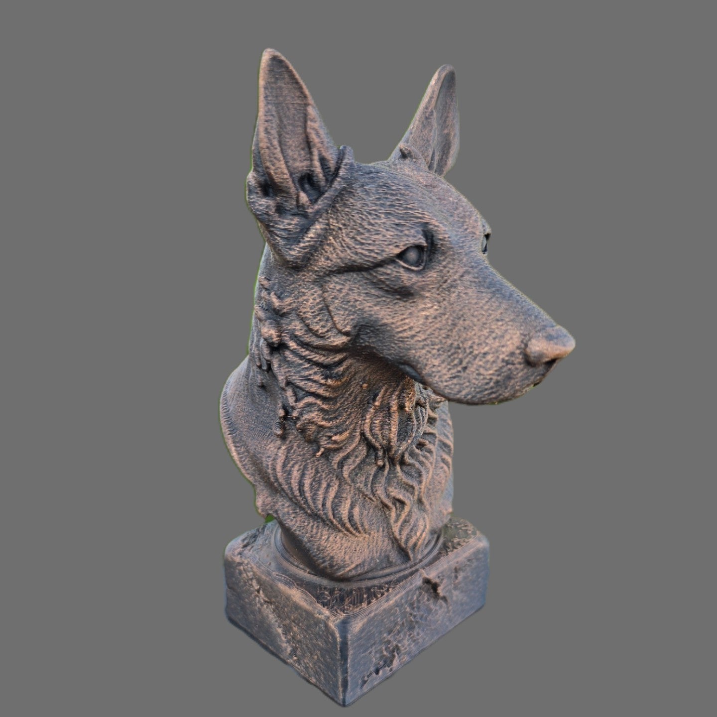 A sculpture of a dog's head on a square pedestal, shown against a solid gray background.
