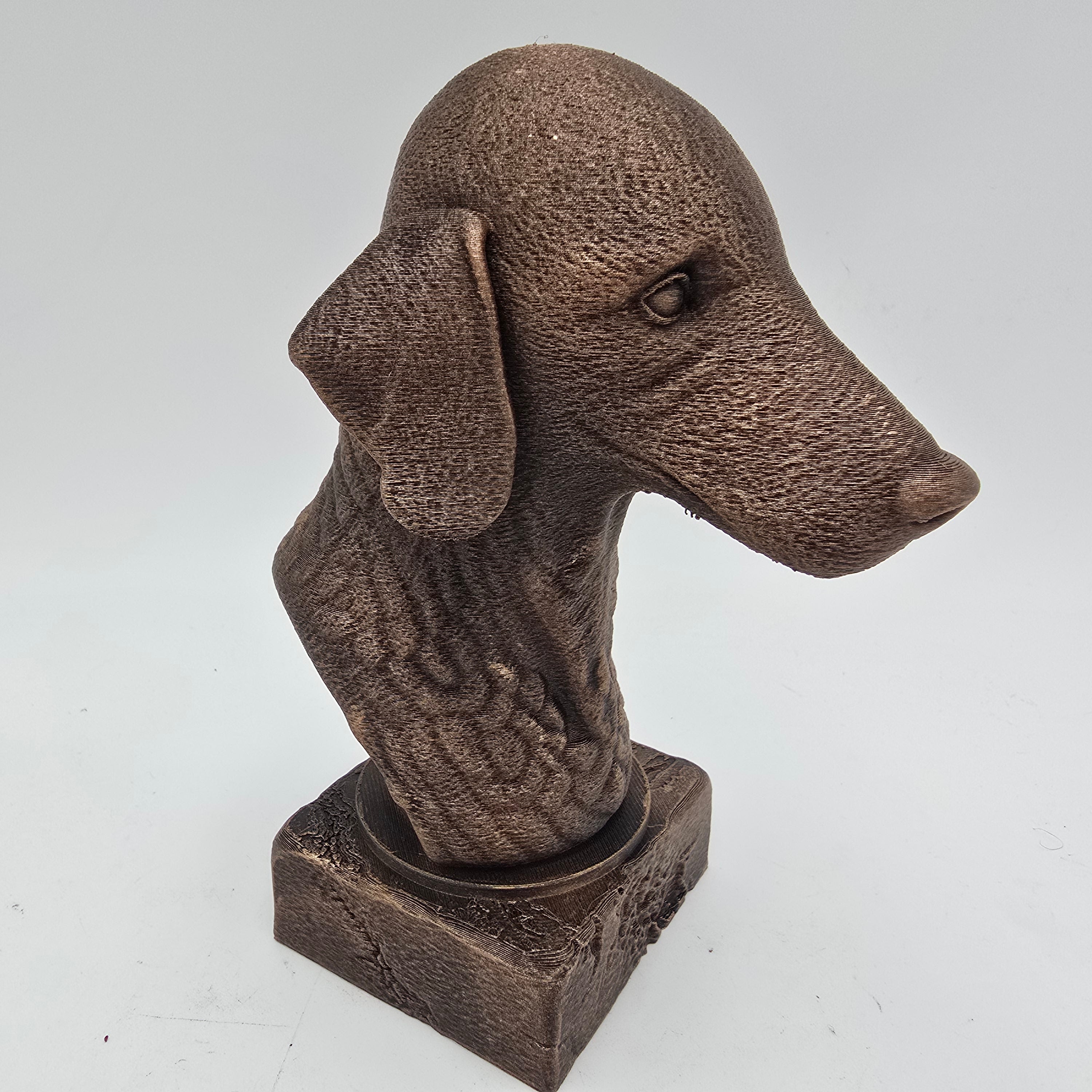 Bedlington terriër hondenbuste in bronskleurige afwerking, schuin van rechts gefotografeerd op een witte achtergrond.