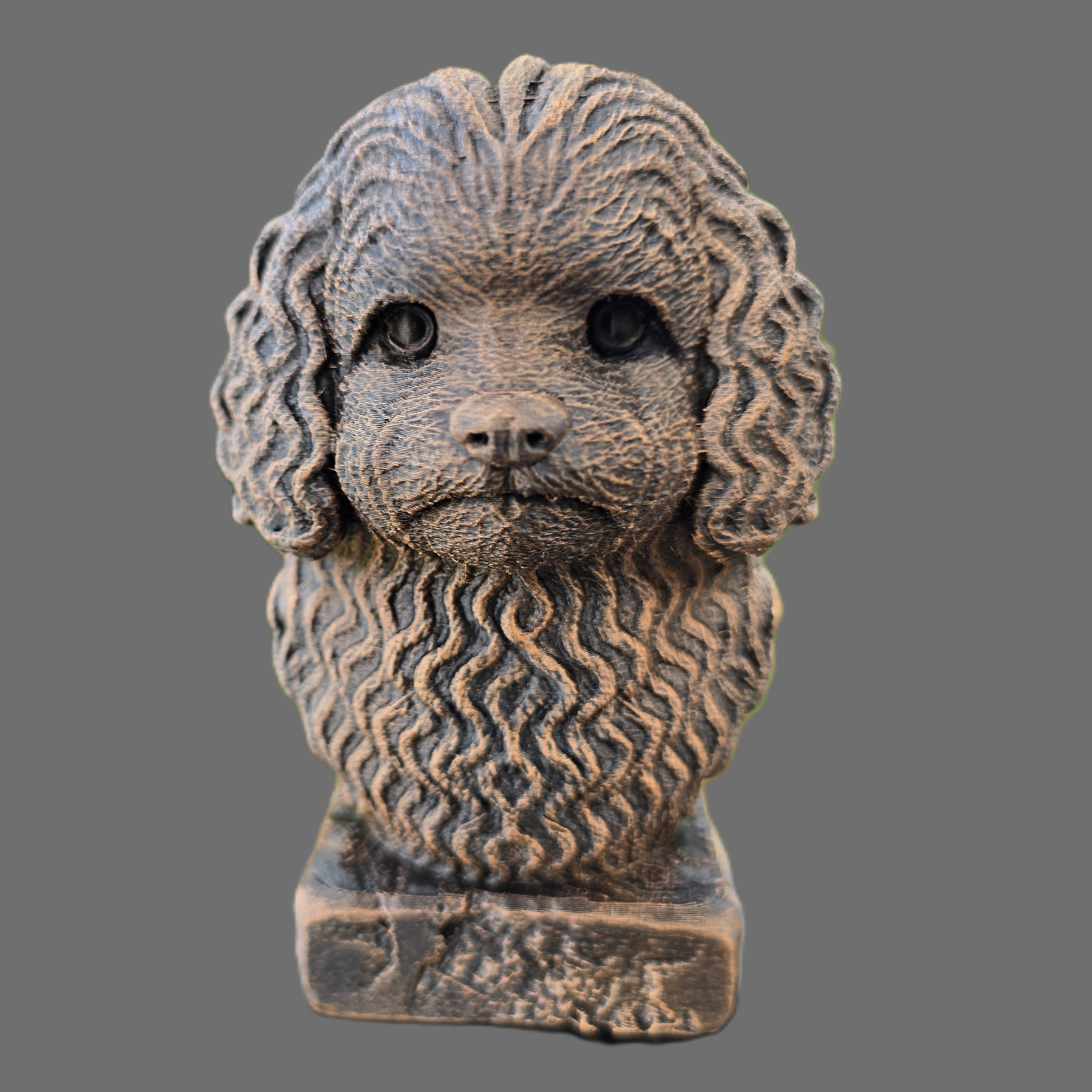 A sculpted decorative bust of a balonka dog, with a textured stone-like finish and dark eyes, set against a solid gray background.