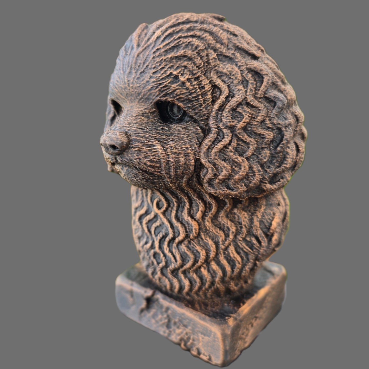 A sculpted decorative bust of a balonka dog on a rectangular base, shown against a plain gray background.