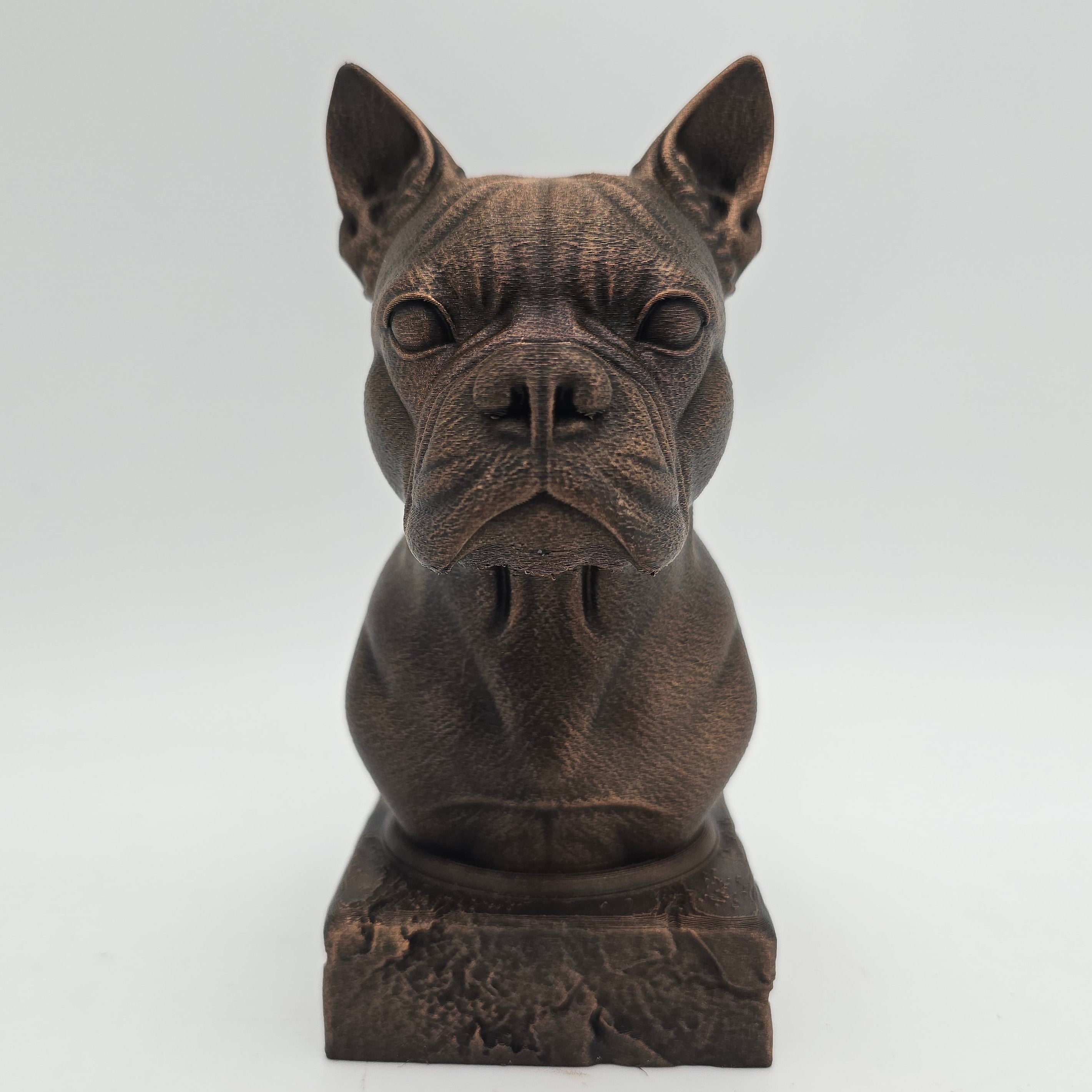 Front view of a bronze Boston Terrier dog bust sculpture with upright ears and a detailed wrinkled face on a decorative pedestal.