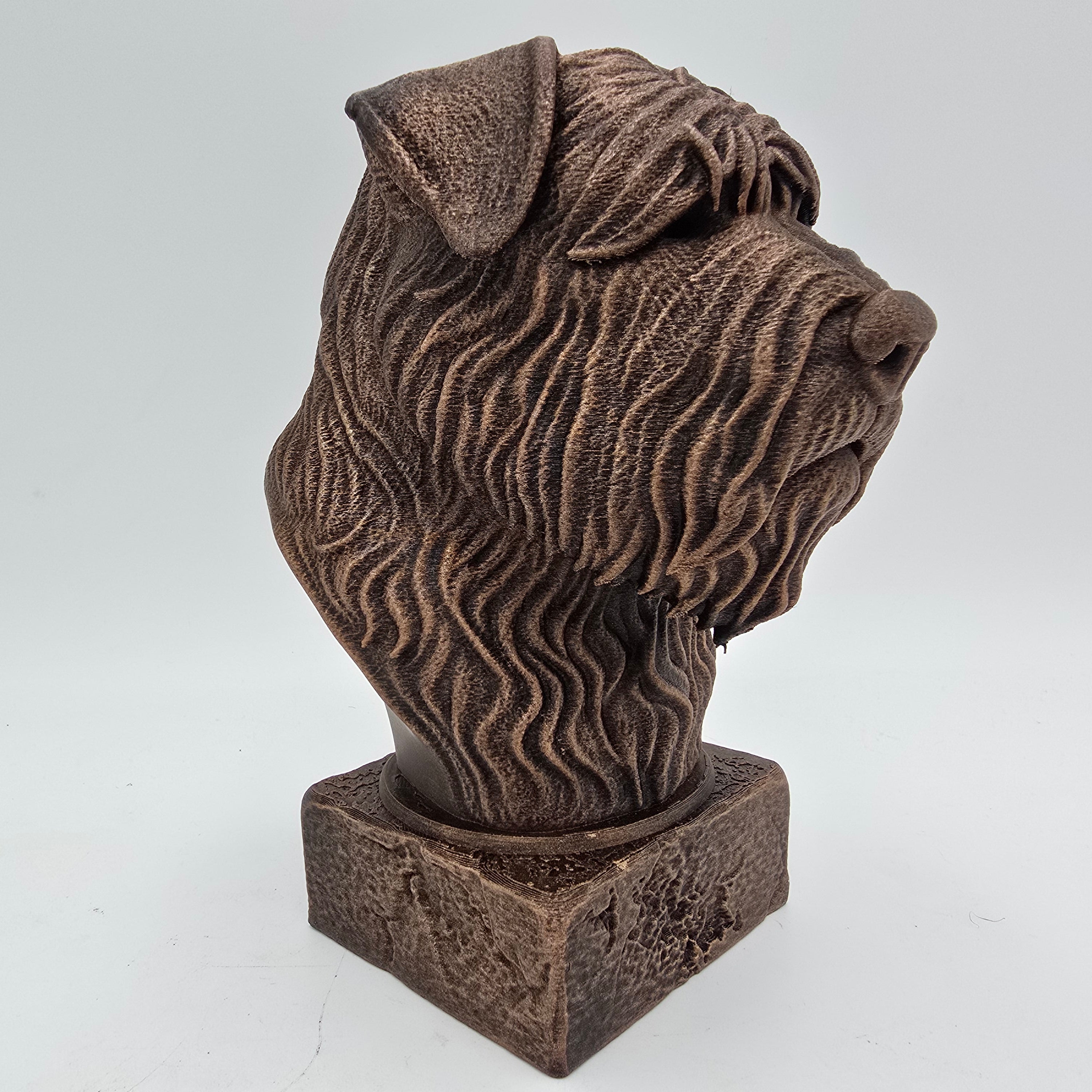 Bronze Bouvier des Flandres dog bust sculpture viewed from the front right, featuring detailed shaggy fur and a distinctive beard on a decorative pedestal.